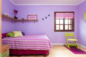 - une chambre violette avec un lit et une chaise jaune dans l'établissement Casa Magdalena - private House with pool, à Chayofa
