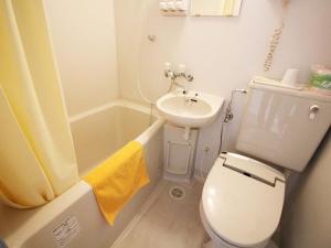 a white toilet sitting next to a bath tub in a bathroom at Hotel Koshien in Nishinomiya
