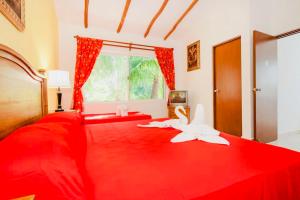 Un dormitorio con una cama roja con dos cisnes. en Gorgeous 22 People Villa With Pool Playacar Phase 2, en Playa del Carmen