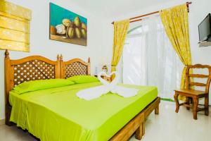 Un dormitorio con una cama verde con una silla y una ventana en Gorgeous 22 People Villa With Pool Playacar Phase 2, en Playa del Carmen
