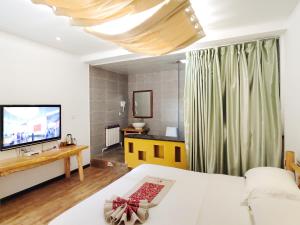a living room with a bed and a television at Dunhuang Silk Yododo Inn in Dunhuang