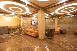 un vestíbulo con sofás y TV en la pared en Vizyon Park Otel, en Sanlıurfa