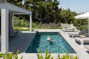 una persona está en el agua en una piscina en Terra Olivia Luxury Villas and Suites, en Paliouri