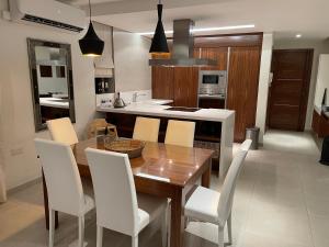 a kitchen with a wooden table and white chairs at Deluxe Apartment with pool in the heart of St Pauls Bay in St. Paul's Bay