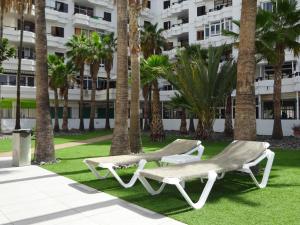 two lounge chairs on the grass in front of a building at Cherry Friendly Holiday Home in Playa del Ingles