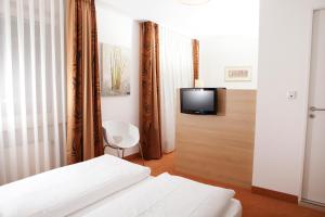 Hotel Flandrischer Hof في كولونيا: غرفة نوم بسرير وتلفزيون على جدار