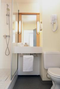 uma casa de banho com um lavatório, um WC e um espelho. em Ibis Saint Étienne - La Terrasse em Saint-Étienne