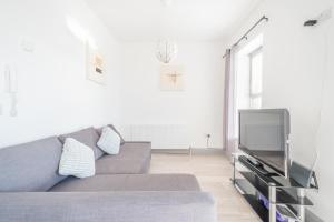 ein Wohnzimmer mit einem grauen Sofa und einem TV in der Unterkunft Portrush Marine Apartments flat1 in Portrush