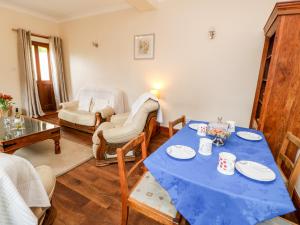 un salon avec une table bleue et des chaises dans l'établissement Gromit Cottage, à Ripon