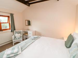 a bedroom with a bed and a desk and a window at Gromit Cottage in Ripon