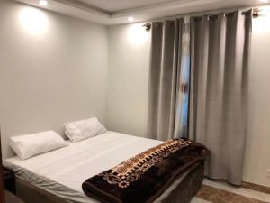 a bedroom with a bed with white sheets and curtains at Hotel Silver Oaks in Narān