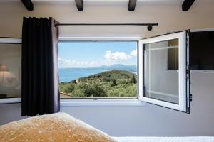 1 dormitorio con ventana grande con vistas en Terra Rossa by Konnect, Views to Ionian Sea, en Spartýlas