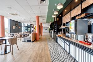 a restaurant with a counter and tables and chairs at B&B HOTEL Le Port Marly Saint Germain en Laye in Le Port-Marly