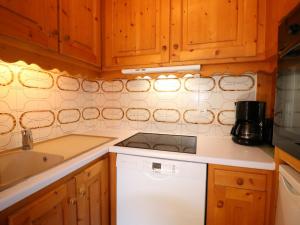 cocina con armarios de madera y lavavajillas blanco en Appartement Méribel, 2 pièces, 5 personnes - FR-1-182-27, en Méribel