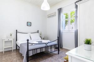 a white bedroom with a bed and a window at PSARIANOS BEACHFRONT APARTMENTS in Panormos Skopelos