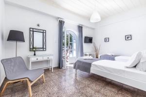 a white bedroom with a bed and a chair at PSARIANOS BEACHFRONT APARTMENTS in Panormos Skopelos