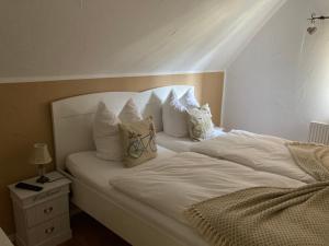 ein Bett mit weißer Bettwäsche und Kissen darauf in der Unterkunft Guest House Dommitzsch in Dommitzsch