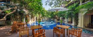 a pool with tables and chairs and an umbrella at Khum Phaya Resort & Spa Boutique Collection in Chiang Mai