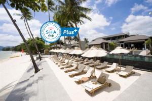 eine Reihe von Liegestühlen und Sonnenschirmen am Strand in der Unterkunft Sareeraya Villas & Suites - SHA Extra Plus in Chaweng