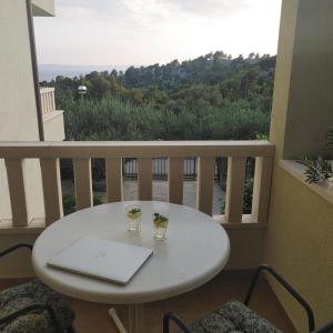 een witte tafel met een laptop op een balkon bij Apartments Villa Čizmić in Baška Voda