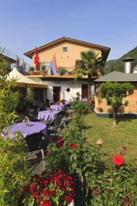 um restaurante com mesas roxas e flores num quintal em Hotel Pensione da Peppino em Cavigliano