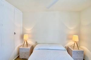 Un dormitorio con dos lámparas y una cama. en Tahití apartamento primera línea de PLaya Muchavista, Wifi, parking, en El Campello