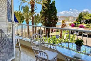 Un balcón con mesa y sillas y palmeras. en Tahití apartamento primera línea de PLaya Muchavista, Wifi, parking, en El Campello