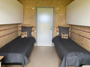 duas camas num quarto com paredes de tijolo em Danhostel Fjaltring em Fjaltring
