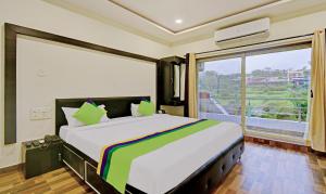 a bedroom with a large bed with a large window at Treebo Trend Paradise Inn Panchgani in Mahabaleshwar
