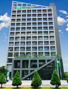 a tall building with trees in front of it at Holiday Inn Express Chiayi, an IHG Hotel in Chiayi City