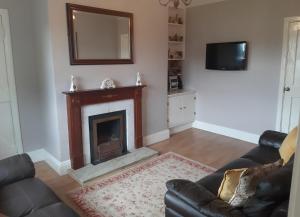 a living room with a fireplace and a mirror at Primrose Cottage in Kinnitty