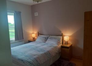 a bedroom with a bed and two lamps on tables at Primrose Cottage in Kinnitty