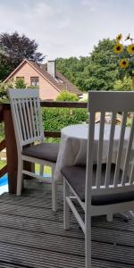 two white chairs and a table on a deck at Apartment bei Paulchen in Schneverdingen