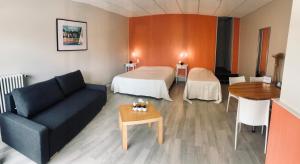 a room with a bed and a couch and a table at Le Clos Fleuri - Maison Vigier in Maringues