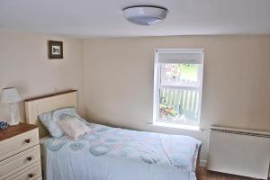 a small bedroom with a bed and a window at Glenbeigh Holiday Cottage - Tigin Mamo in Glenbeigh