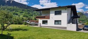 une maison avec une pelouse verte devant dans l'établissement Ferienwohnung Willi, à Schruns