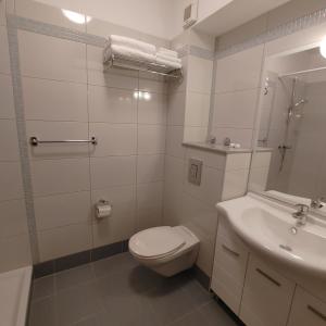a white bathroom with a toilet and a sink at Apartments Villa Čizmić in Baška Voda