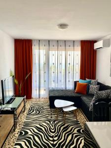 uma sala de estar com um sofá preto e cortinas vermelhas em Byala Solita Apartament em Byala