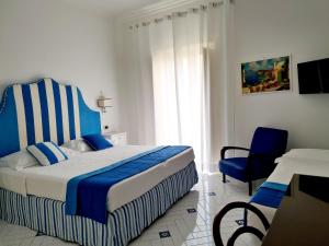 a bedroom with a blue and white bed and a chair at Hotel Villa Di Sorrento in Sorrento