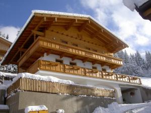 a building with a wooden balcony in the snow at Knollnwies in Alpbach