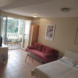 d'un salon avec un canapé rouge et un balcon. dans l'établissement Apartments Villa Čizmić, à Baška Voda
