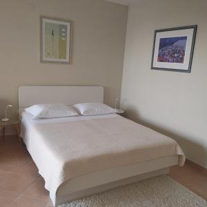 a bedroom with a white bed with a picture on the wall at Apartments Villa Čizmić in Baška Voda