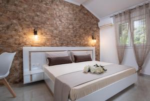 a bedroom with a large white bed and a brick wall at Estell apartments in Sykia Chalkidikis