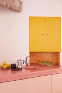 a kitchen with yellow cabinets and a pink counter top at Kimolos View in Kimolos +10 photos