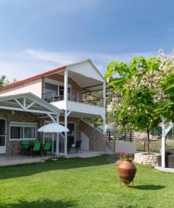 a house with a porch and chairs and an umbrella at Estell apartments in Sykia Chalkidikis