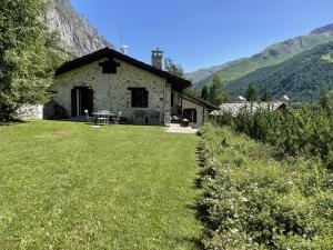 a stone house with a grass yard in front of it at L'Atelier du Temps - Baita Grandes Jorasses in Montita
