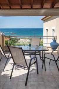 a table and chairs on a patio with a view of the ocean at Limnos IRiS Apartments in Agios Ioannis Kaspaka