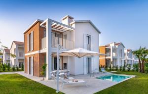 a villa with a swimming pool and an umbrella at Pareus Beach Resort in Caorle