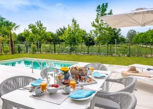a white table with breakfast food on it next to a pool at Pareus Beach Resort in Caorle