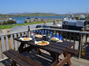 una mesa de madera con 2 platos de comida en el balcón en Oliver's Seafood Bar, Bed & Breakfast, en Cleggan
